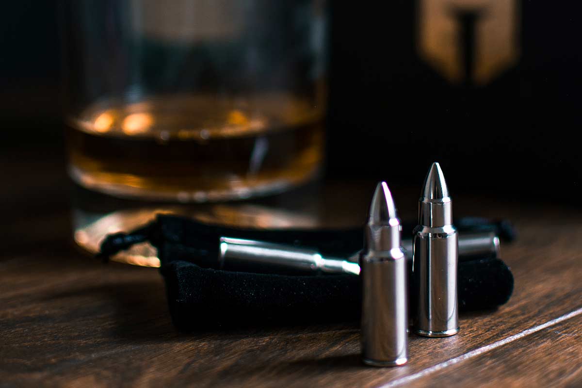 a gun, bullets and alcoholic drink on a table