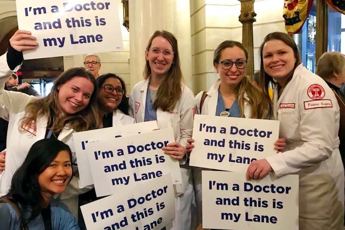 Group of doctors holding up signs "I am a doctor and this IS my lane"