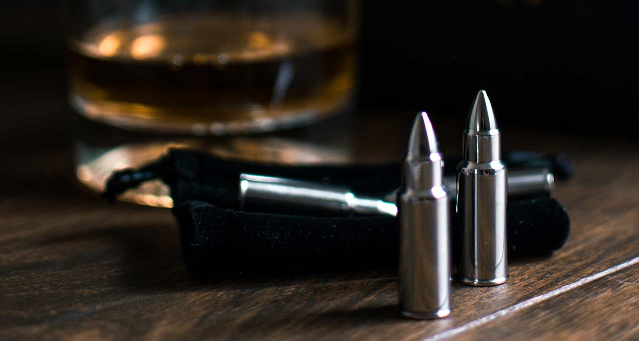 glass of alcohol, gun and bullets on a table