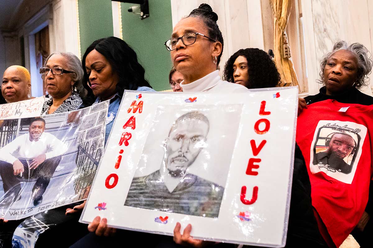 woman holds up a sign commemorating her dead loved one