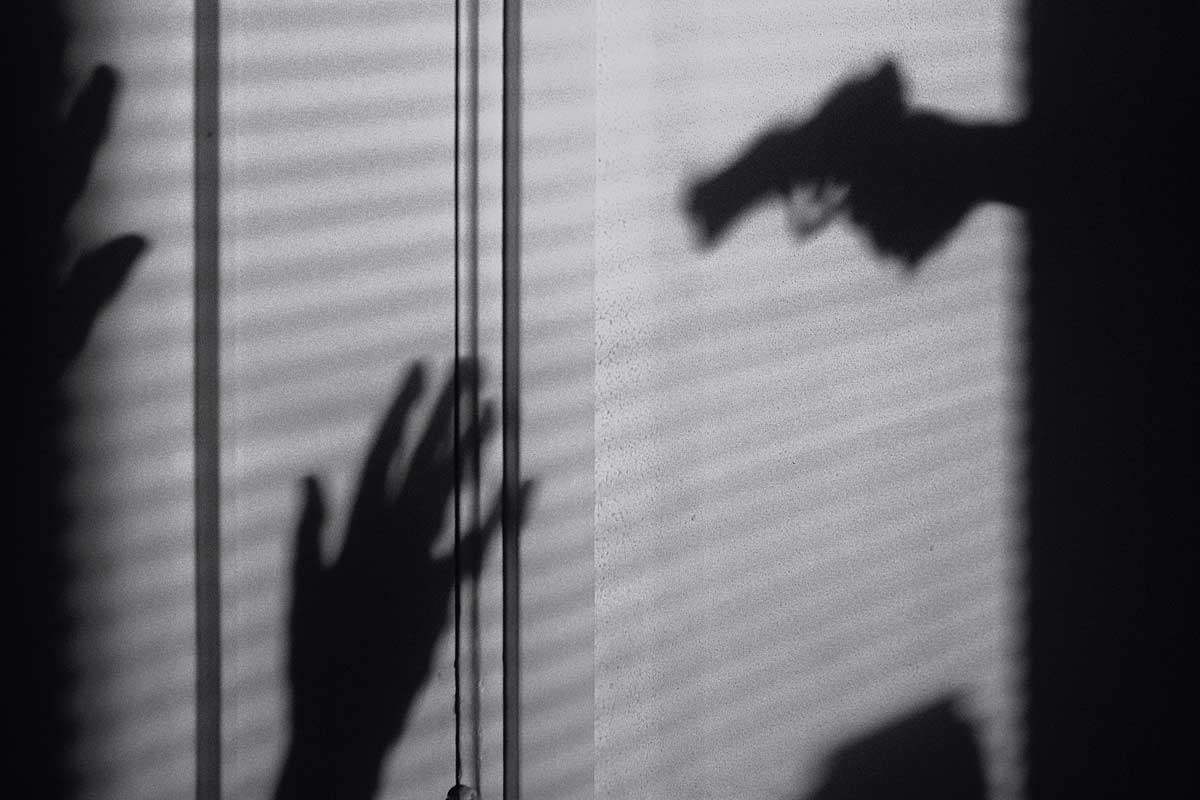 silhouette of gun aimed at hands up